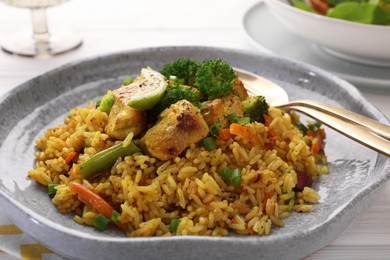 Photo of Tasty rice with meat and vegetables in plate served on white wooden table, closeup