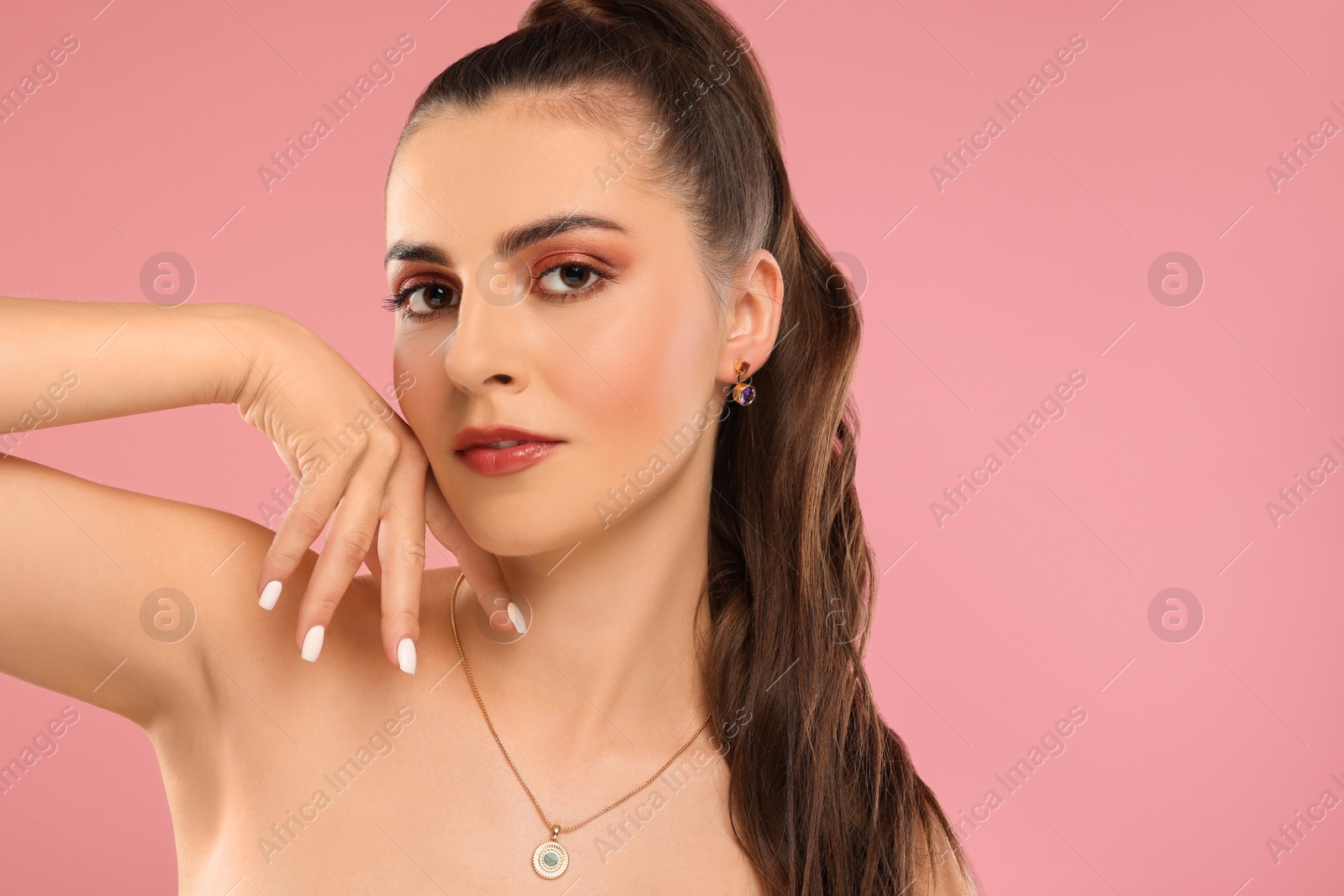 Photo of Beautiful woman with elegant jewelry on pink background, space for text