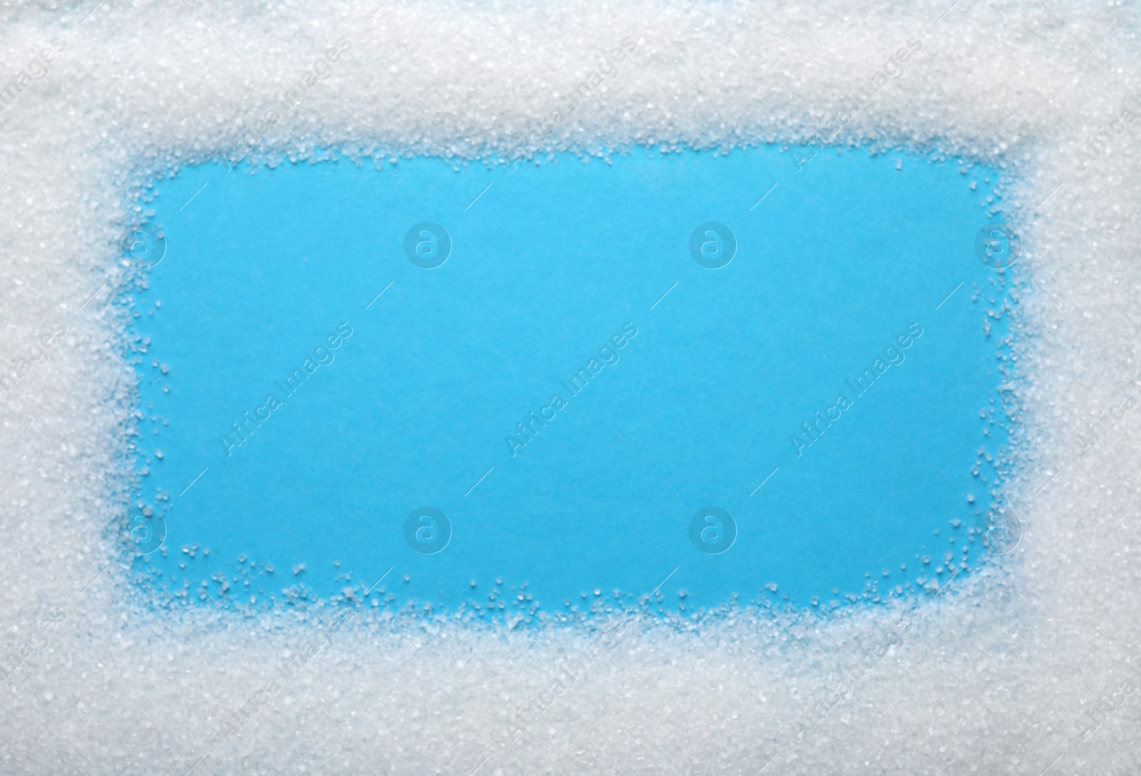 Photo of Frame made of granulated sugar on light blue background, top view. Space for text