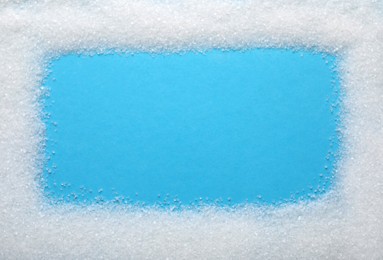 Photo of Frame made of granulated sugar on light blue background, top view. Space for text