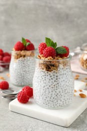 Photo of Delicious chia pudding with raspberries and granola on grey table