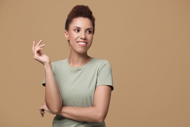 Portrait of beautiful young woman on light brown background. Space for text