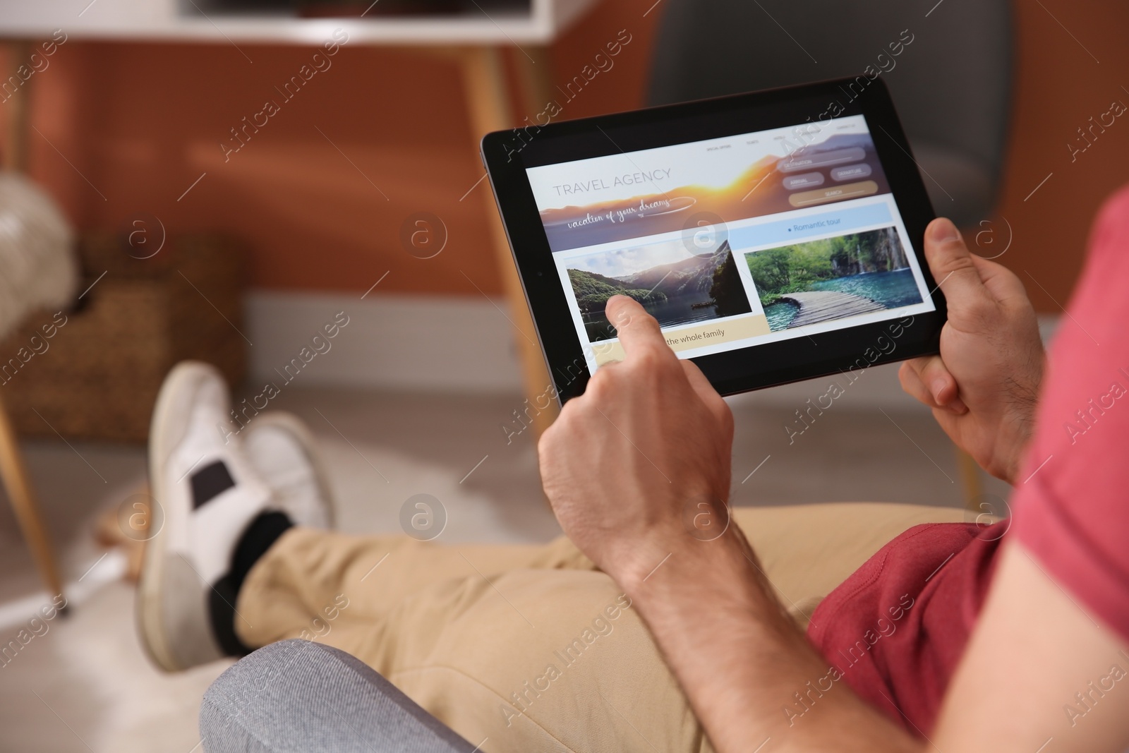 Photo of Man with tablet booking tickets online at home, closeup. Travel agency concept