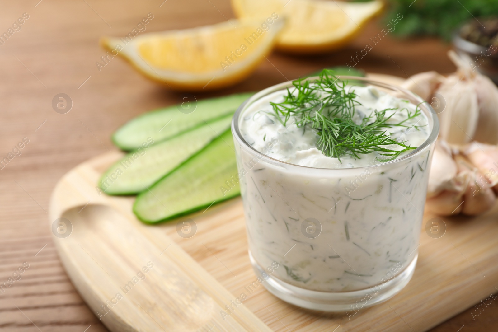 Photo of Cucumber sauce with ingredients on wooden background, space for text. Traditional Tzatziki