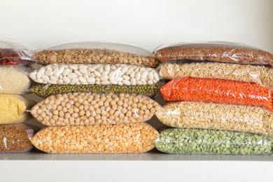Different types of legumes and cereals in plastic bags on shelf. Organic grains