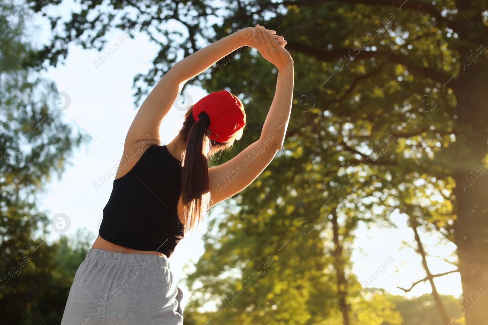 Photo of Young woman doing morning exercise in park, back view. Space for text