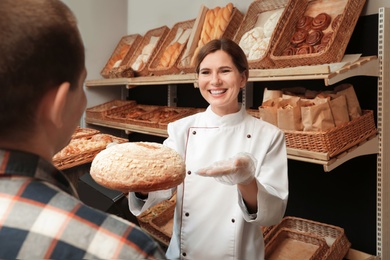 Baker giving customer fresh bread in store