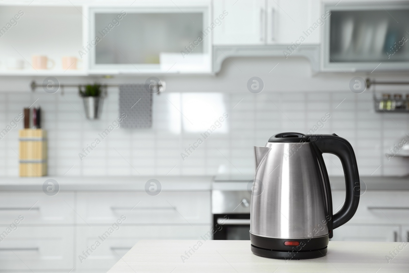 Photo of Modern electric kettle on wooden table in kitchen. Space for text