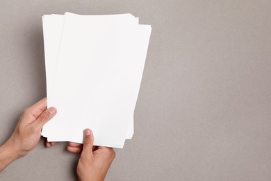 Photo of Man holding sheets of paper on grey background, closeup. Mockup for design