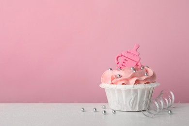 Photo of Baby shower cupcake with topper on white table against pink background, space for text