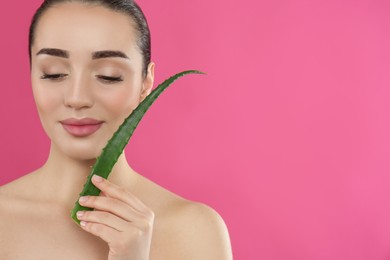 Photo of Young woman with aloe vera leaf on pink background. Space for text