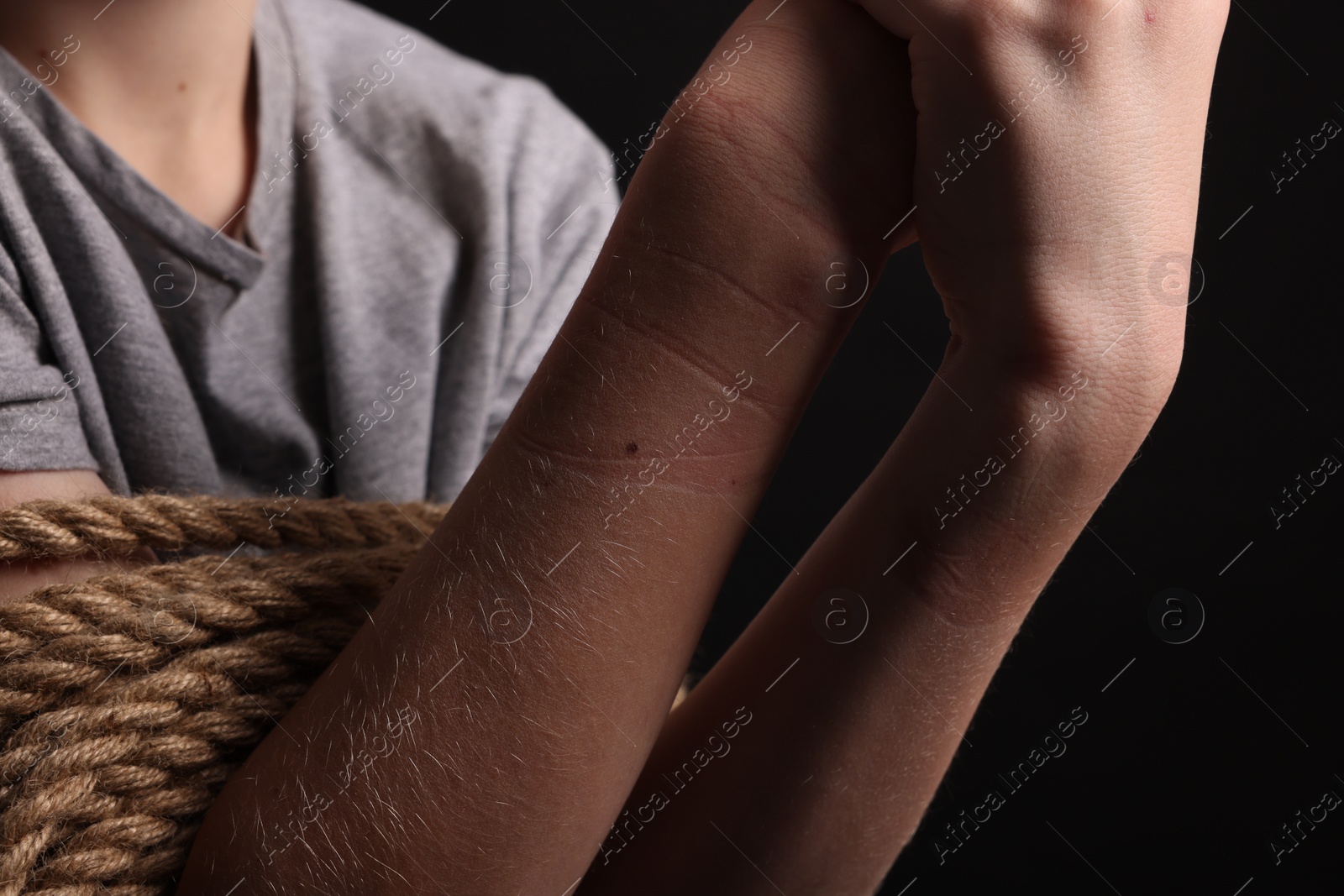 Photo of Little boy tied up and taken hostage on dark background, closeup
