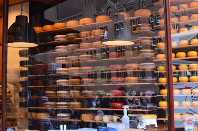 Amsterdam, Netherlands - June 25, 2022: Many cheese wheels on shelves, view through glass window
