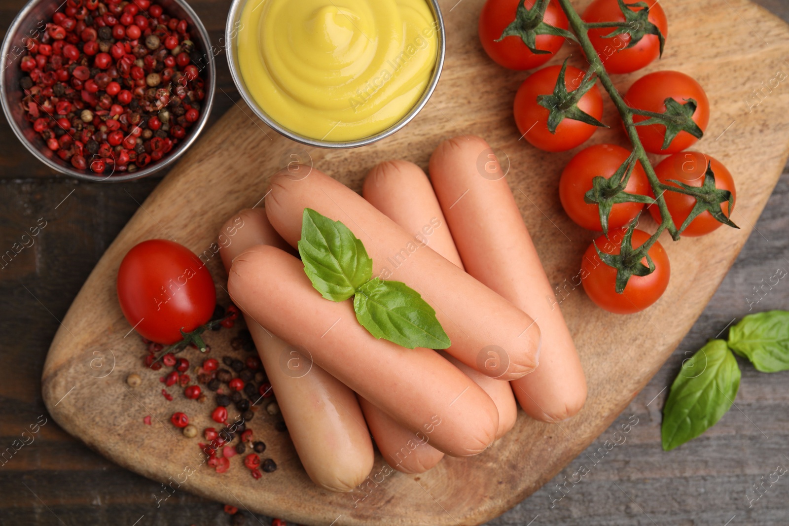 Photo of Delicious boiled sausages, sauce, tomatoes and spices on wooden table, flat lay