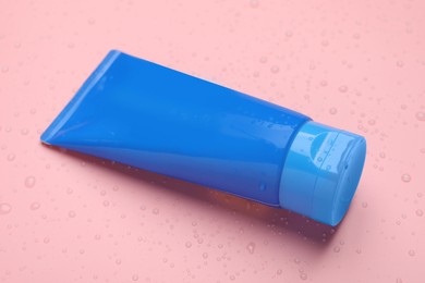 Photo of Wet tube of face cleansing product on pink background