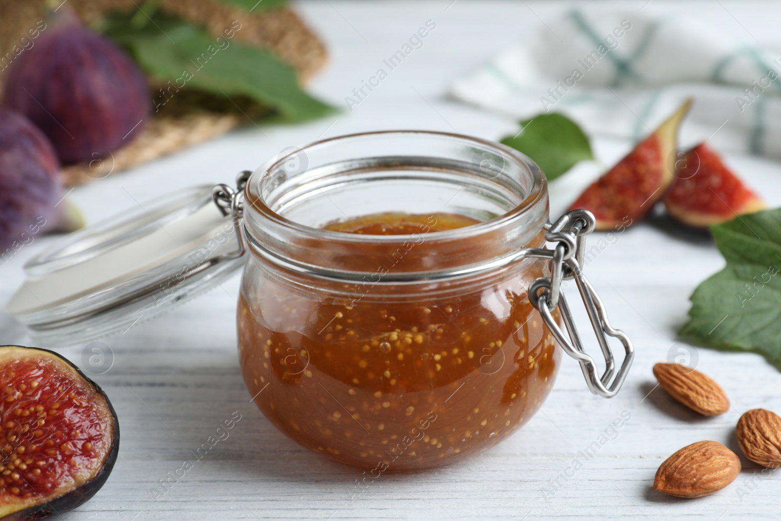 Photo of Delicious fig jam on white wooden table, closeup