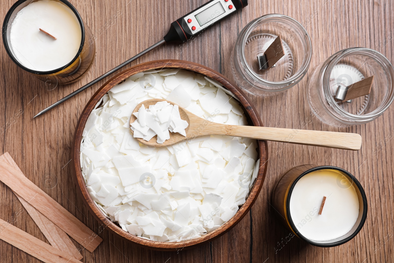 Photo of Flat lay composition with homemade candles  and ingredients on wooden background