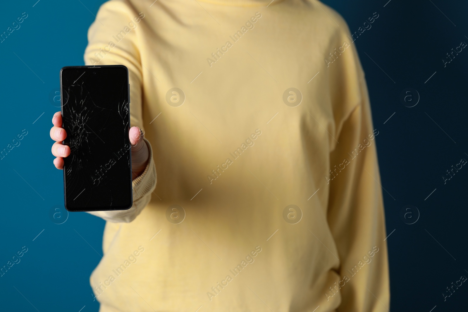 Photo of Woman showing damaged smartphone on light blue background, closeup. Device repairing