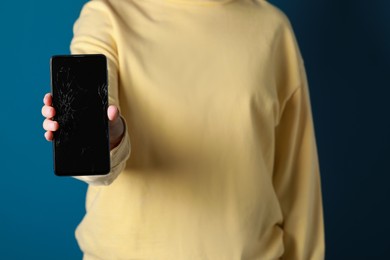 Photo of Woman showing damaged smartphone on light blue background, closeup. Device repairing