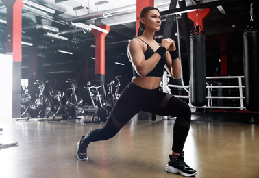 Photo of Young woman doing lunges in modern gym