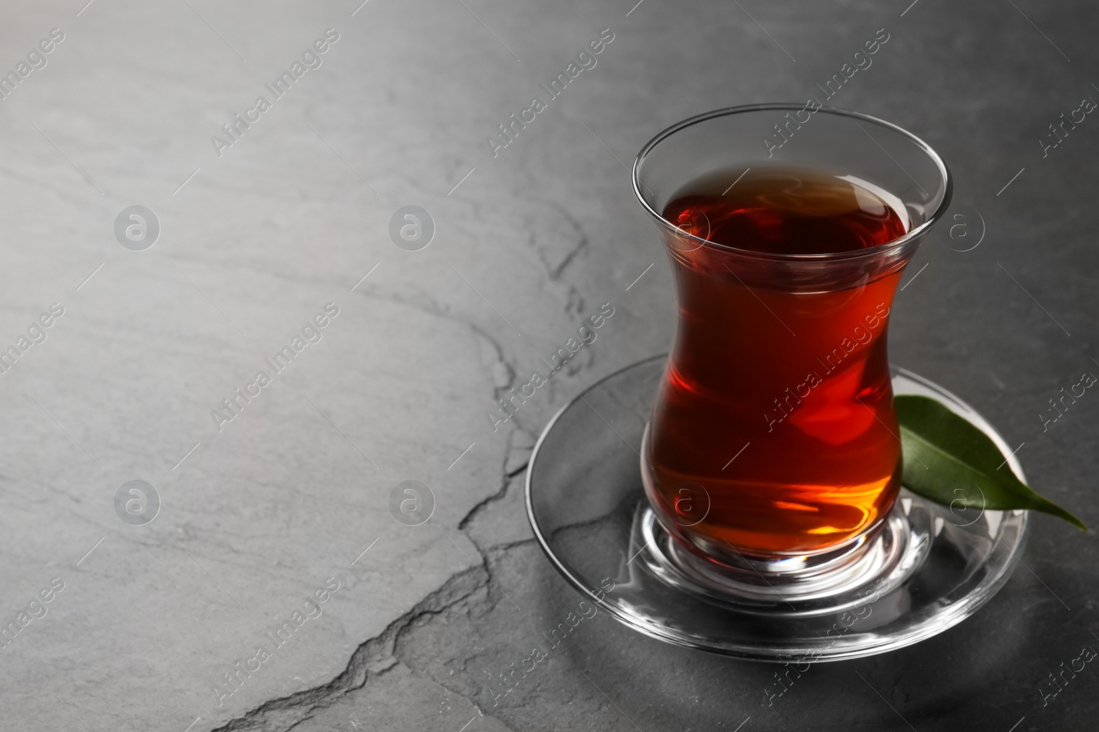 Photo of Glass with traditional Turkish tea on black table. Space for text