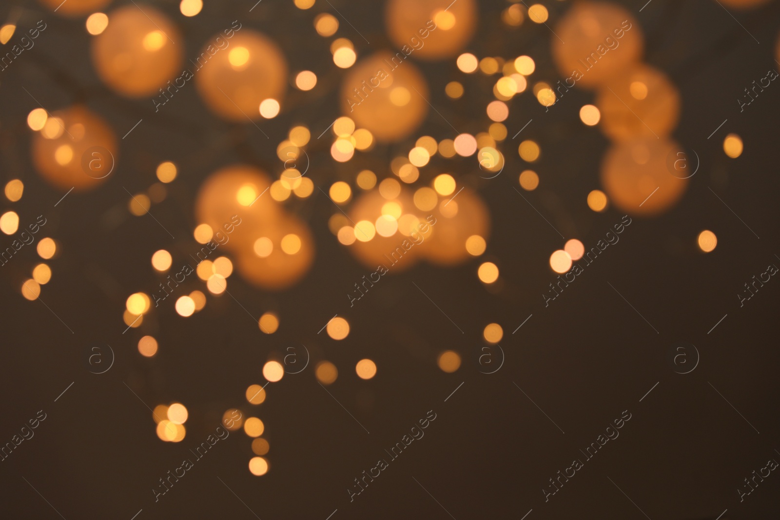 Photo of Blurred view of gold lights on dark background. Bokeh effect