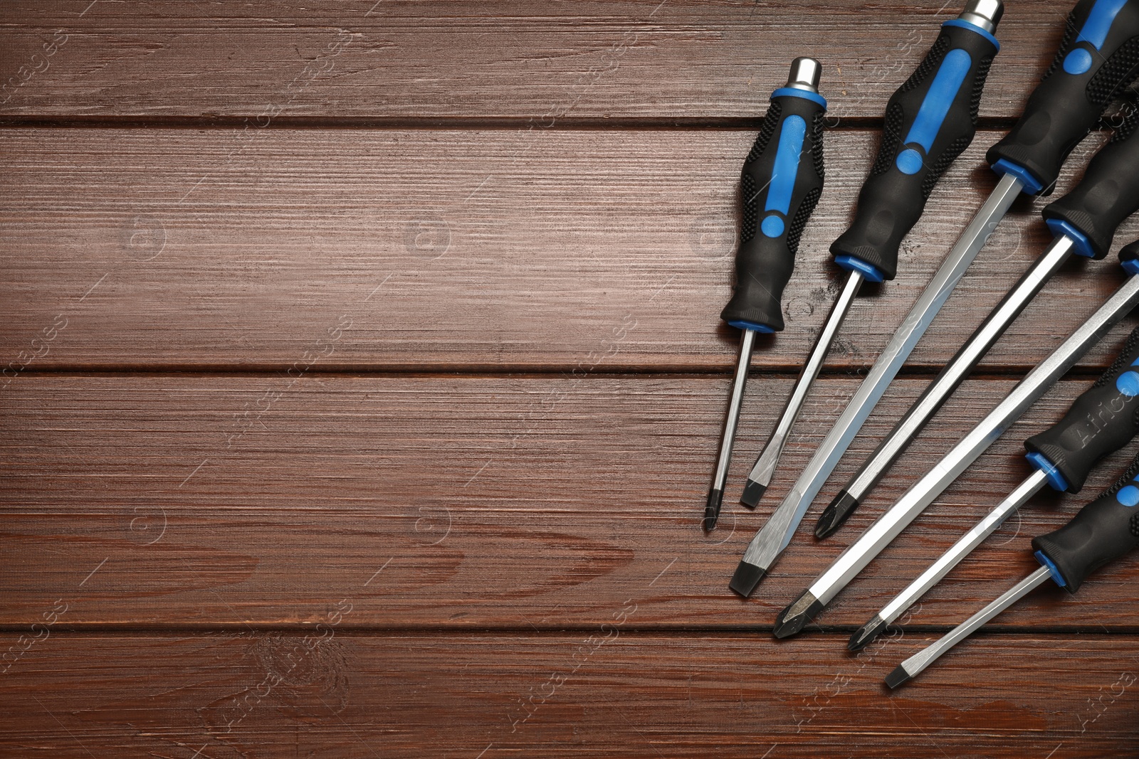 Photo of Set of screwdrivers on wooden table, top view. Space for text