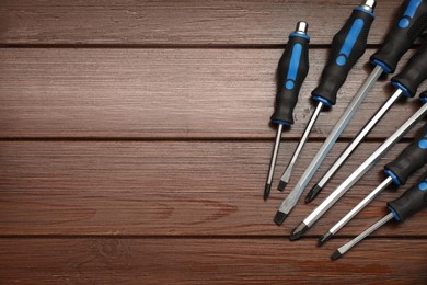 Set of screwdrivers on wooden table, top view. Space for text