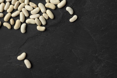 Photo of Raw beans and space for text on black background, flat lay. Vegetable seeds