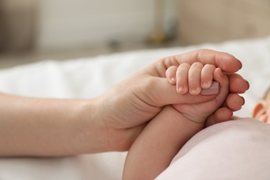 Photo of Mother holding baby's hand on blurred background, closeup