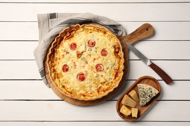 Photo of Delicious homemade cheese quiche, ingredients and knife on white wooden table, flat lay