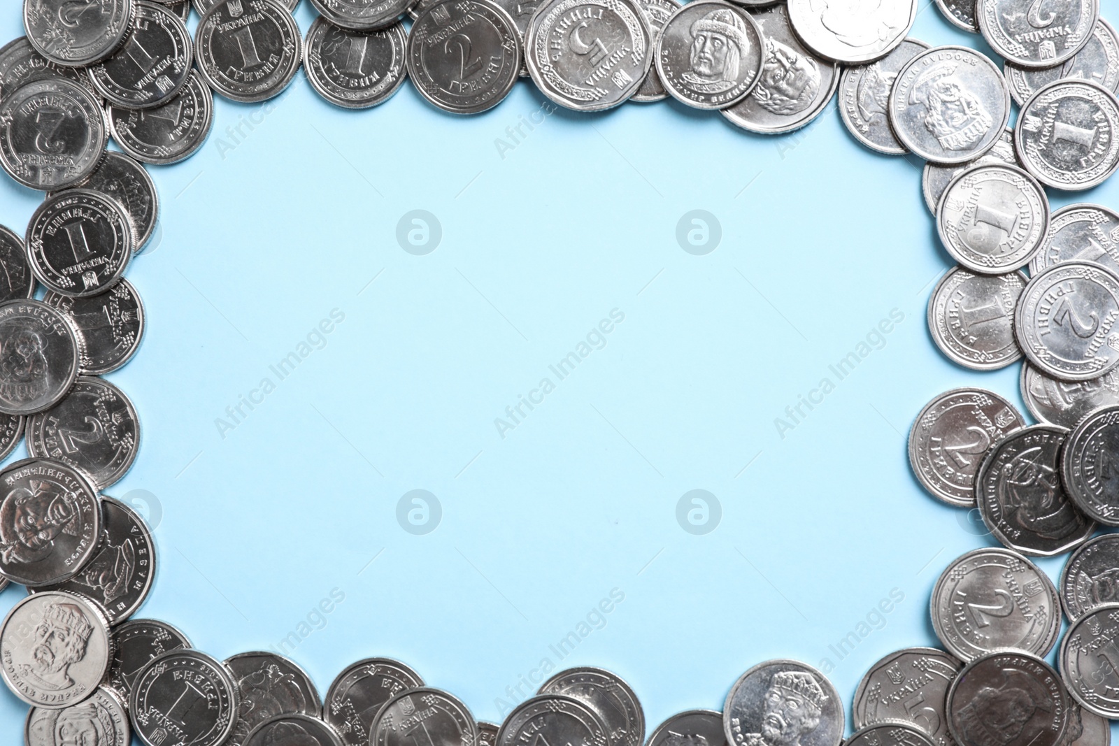 Photo of Frame of Ukrainian coins on light blue background, flat lay. Space for text