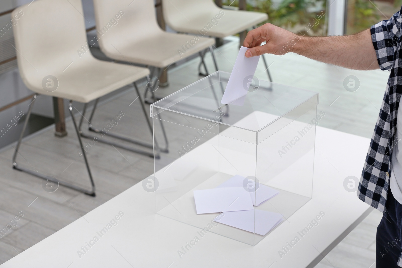 Photo of Man putting his vote into ballot box at polling station, closeup