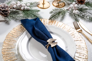 Photo of Stylish table setting with dark blue fabric napkin, beautiful decorative ring and festive decor