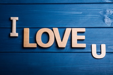 Photo of Phrase I Love U on blue wooden background, flat lay