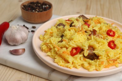 Photo of Delicious pilaf with meat and ingredients on wooden table, closeup