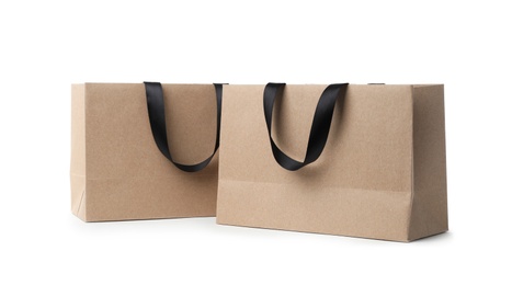 Paper shopping bags with ribbon handles on white background. Mockup for design