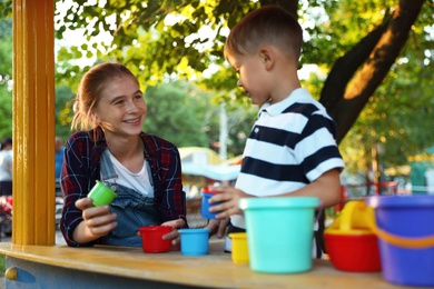 Teen nanny and cute little boy playing outdoors