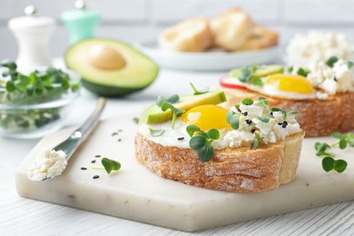 Photo of Delicious sandwiches with egg, cheese, avocado and microgreens on white wooden table, closeup