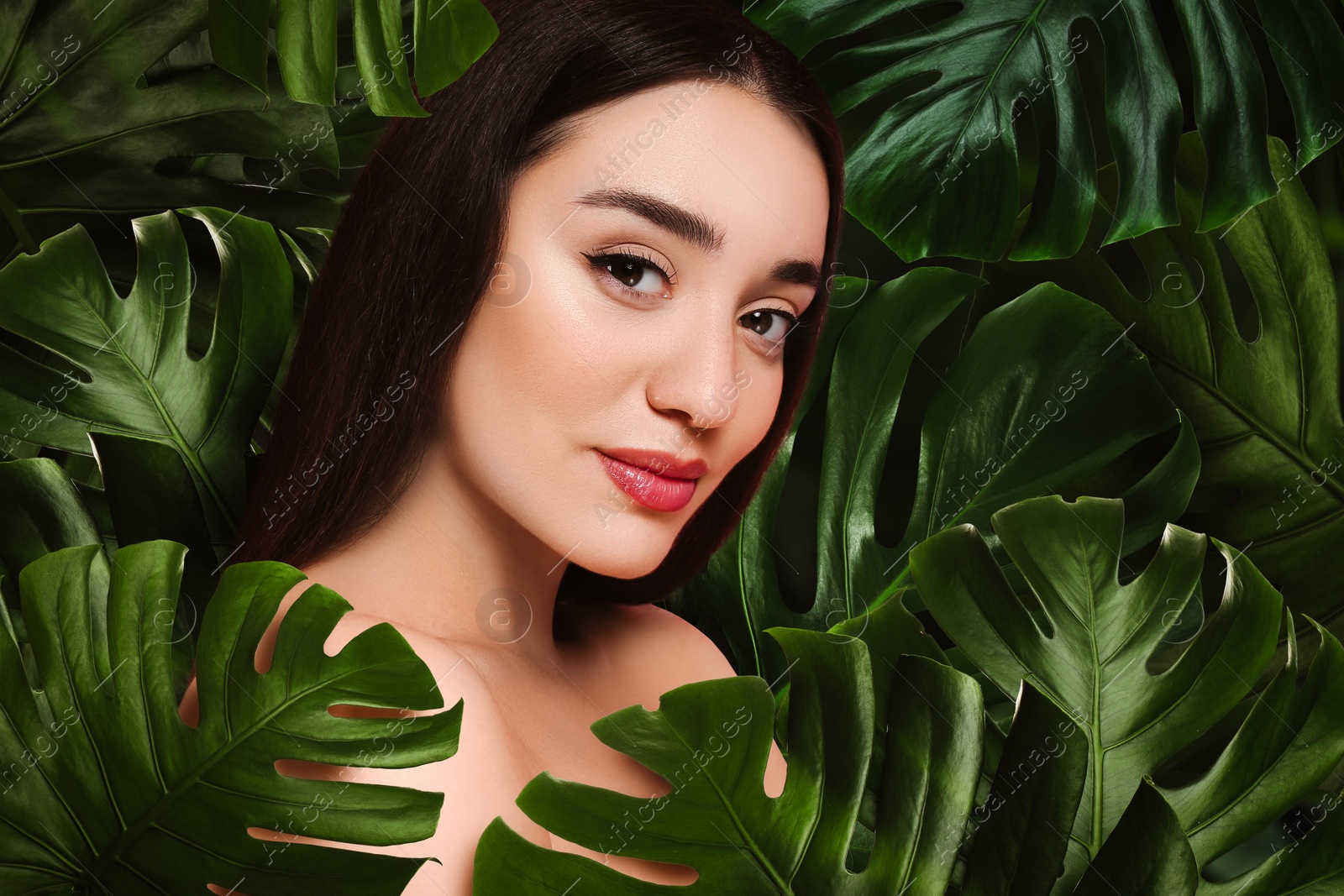 Image of Beautiful young woman feeling harmony while enjoying nature. Girl surrounded by green leaves