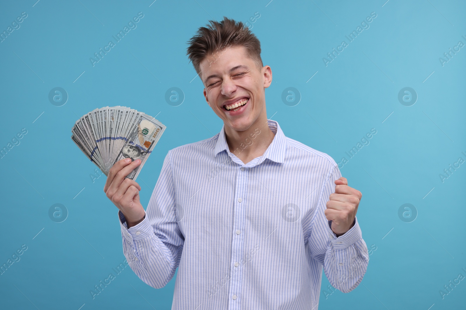 Photo of Happy man with dollar banknotes on light blue background