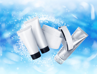 Different cosmetic products on light blue background with bokeh effect. Winter skin care