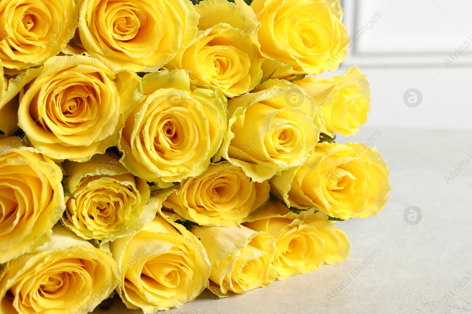 Photo of Beautiful bouquet of yellow roses on light grey table, closeup