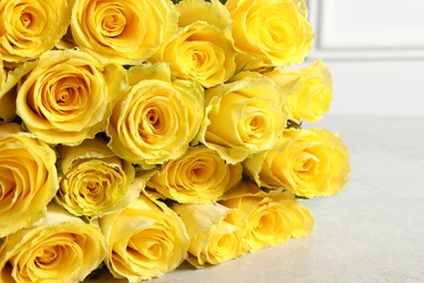 Photo of Beautiful bouquet of yellow roses on light grey table, closeup