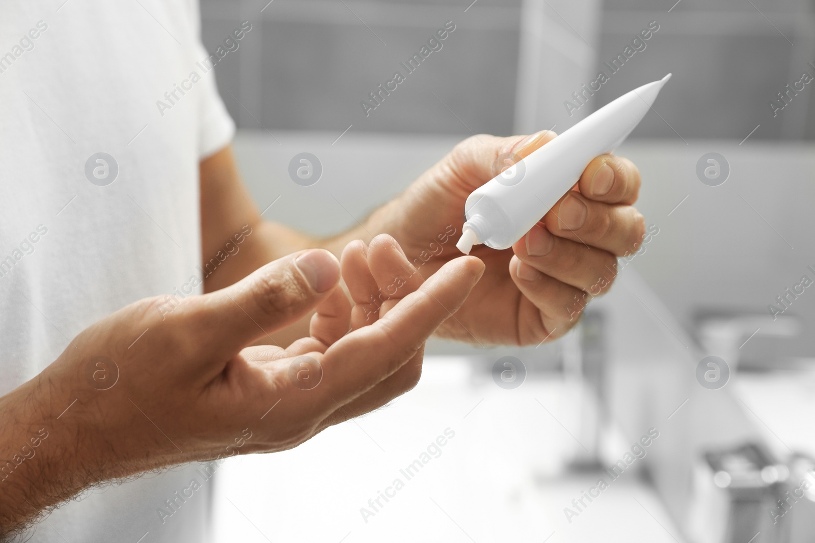 Photo of Handsome man applying cream in bathroom, closeup