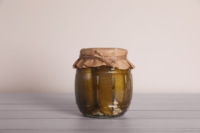 Photo of Jar with pickled cucumbers on white wooden table