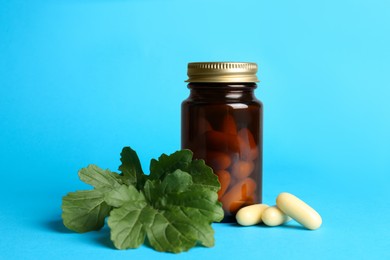 Medical bottle with pills and arugula on light blue background