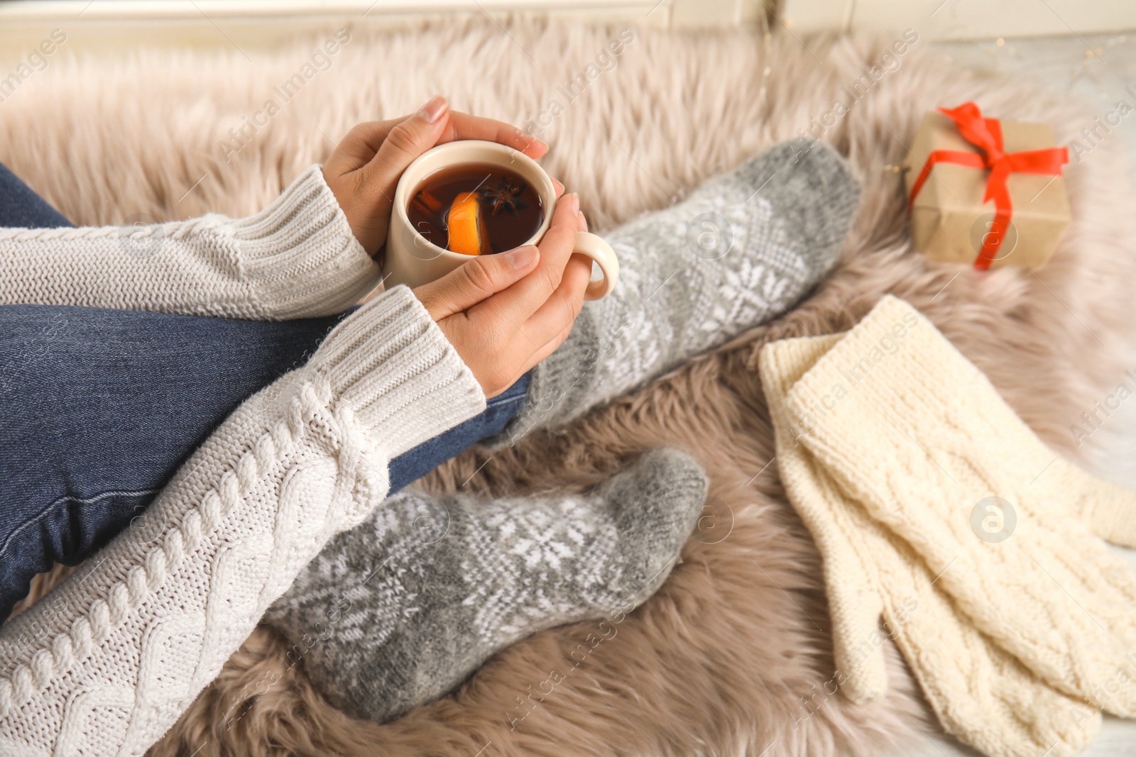 Photo of Woman with cup of hot mulled wine indoors, closeup. Winter drink