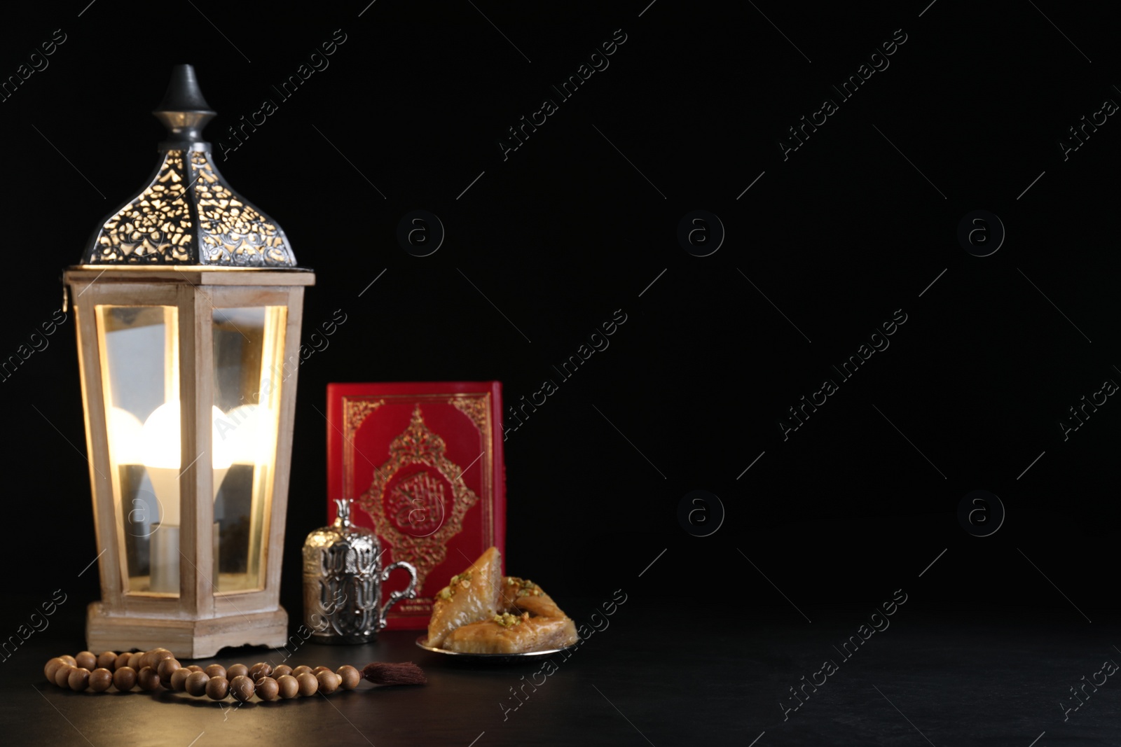 Photo of Composition with Arabic lantern and quran on black table. Space for text