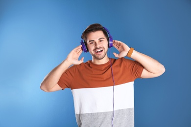 Handsome man with headphones enjoying music on color background